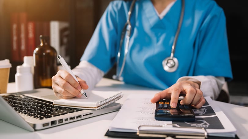 Nurse managing hospital finances by doing accounting calculations
