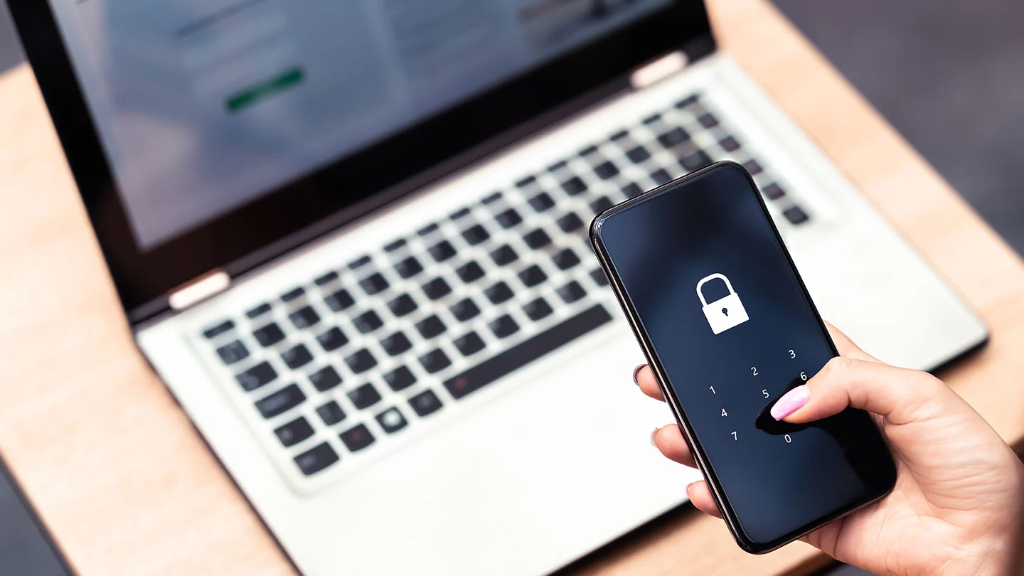 Cybersecurity photo showing a laptop and mobile phone with lock screen.